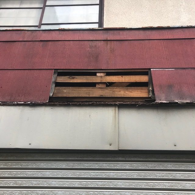 店舗正面の外壁仕上げ材が一部剥がれている
